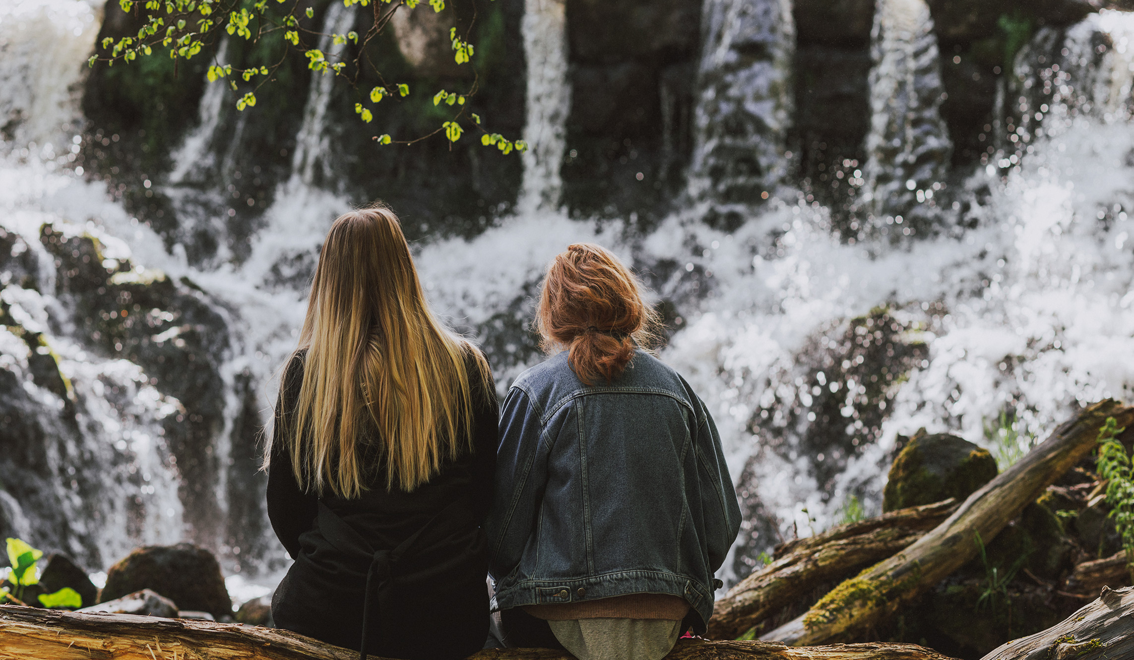 Two persons enjoying a break overlooking a beautiful waterfall.